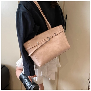 Detailansicht einer rosa Modetasche mit Schnalle, getragen von einem Modell für den Alltag
