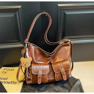 Detail of vintage brown leather tote bag showing textured finish and metal buckle front pockets