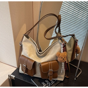 Detail of canvas tote bag featuring brown leather trim and cute plush bear charm