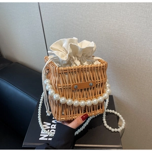 Detail of hand-woven straw bucket bag with pearl handle and canvas drawstring lining