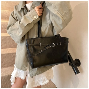 Detailansicht der schwarzen glänzenden Leder-Tote-Bag mit Schnallenriemen auf der Treppe