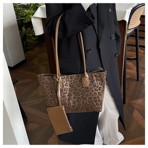 Detail view of leopard print tote bag with brown faux leather handles and small pouch