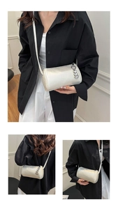 Detail of silver cylinder bag featuring a metallic finish and heart charm accents