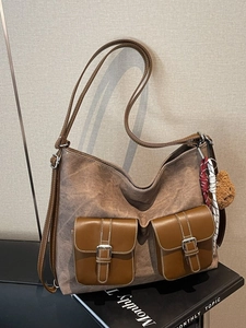 Vintage brown canvas tote bag with leather pockets and a small bear keychain accessory