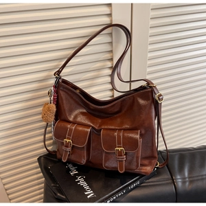 Detail of vintage brown tote featuring dual front pockets with gold buckles and contrast stitching