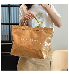 Dettaglio della borsa tote in PVC impermeabile con trama carta spiegazzata marrone e logo