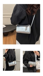 Detail of silver cylinder bag with heart charms and metal chain strap on model