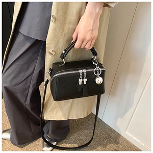 Detail of a black leather box handbag with silver zipper hardware on a fashion model
