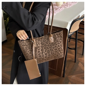 Detail view of large leopard print suede tote with leather handles on a model