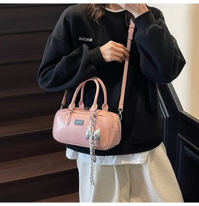 Detalle del bolso bowling de cuero sintético rosa con colgante de lazo plateado y correa