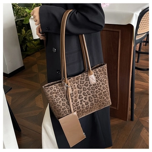 Detail of leopard print tote bag with small pouch shown on model in a cafe setting