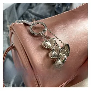 Detailed close-up of rose gold cylinder bag with polished heart-shaped metal charms