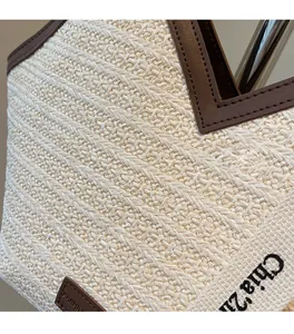 Dettaglio borsa tote in paglia intrecciata con finiture in pelle e tracolla jacquard