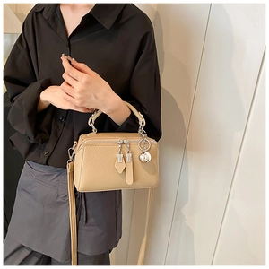 Detail of a beige Boston bag with lychee texture and silver metal ball pendant