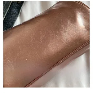 Macro shot of metallic bronze cylinder bag showing leather texture and fine stitching detail