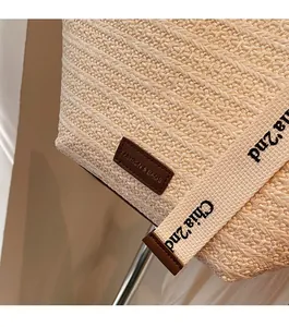 Dettaglio della borsa in paglia intrecciata con inserto in pelle e tracolle in nastro