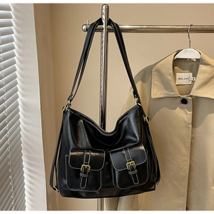 Detail of black leather tote bag featuring dual front pockets and white contrast stitching