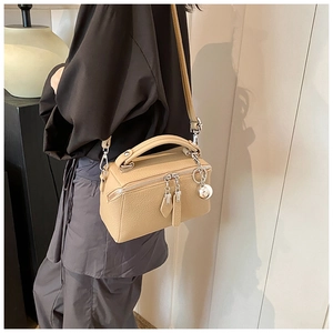 Detail of beige lychee textured leather Boston bag with a silver sphere charm