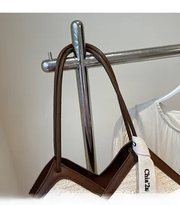 Dettaglio borsa tote in paglia intrecciata con manici in pelle marrone e nastro decorato