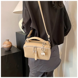 Detail of khaki pebbled leather boston bag with silver sphere charm and adjustable strap
