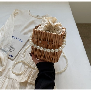 Detailed view of handmade woven straw bucket bag with pearl handle and drawstring lining