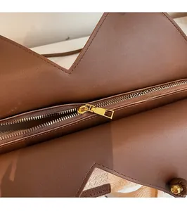 Dettaglio macro della cerniera in metallo dorato su una borsa tote in paglia intrecciata
