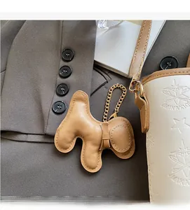 Dettaglio charm per borsa a forma di cane in pelle marrone con cuciture e catena oro