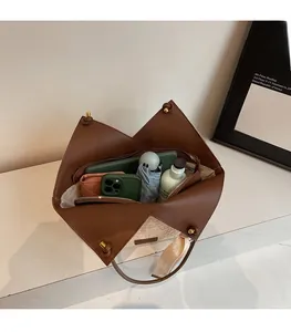 Dettaglio della borsa tote in paglia intrecciata e pelle marrone con ampio interno