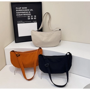 Detailed display of crescent bags in beige, orange, and black with adjustable straps
