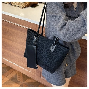 Detail of a black leopard print suede tote bag with a matching small zipper pouch on a strap