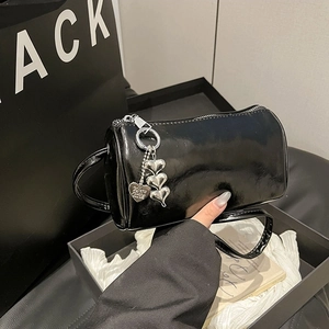 Glossy black cylindrical handbag with silver heart charm and luxury gift packaging