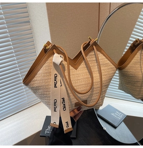 Dettaglio borsa tote in paglia intrecciata con manici in pelle marrone e nastro decorativo
