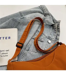 Detail view of orange nylon dumpling bag with adjustable strap and smooth zipper closure