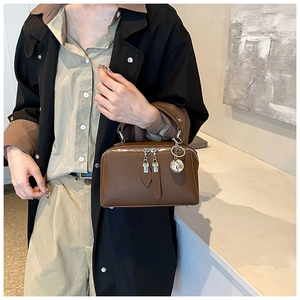 Detail view of brown pebbled leather texture with silver zipper and sphere metal charm