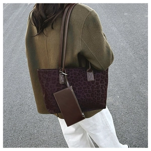 Outdoor shot of a large leopard print suede tote bag with a small brown leather pouch accessory