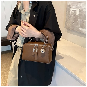 Detail view of dark brown pebbled leather Boston bag with silver ball charm and zip