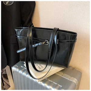 Nahaufnahme der glänzenden schwarzen Tote Bag aus Kunstleder mit Faltenoptik und Metallschnalle