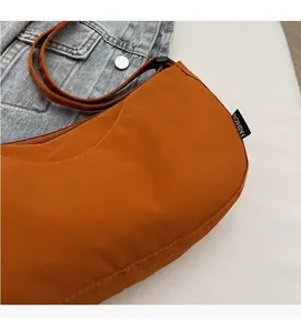 Detail of fashion textile shoulder bag in caramel orange with side label and wide strap