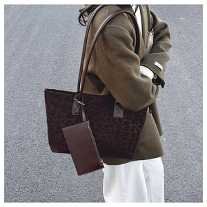 Detail view of large leopard print suede tote bag with brown leather strap and small pouch