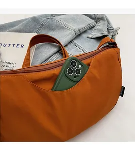Detail showing orange nylon dumpling bag with front zipper pocket and phone storage capacity