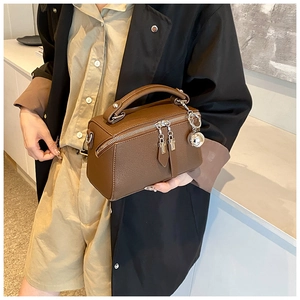 Close-up of brown litchi pattern leather Boston bag with spherical metal pendant