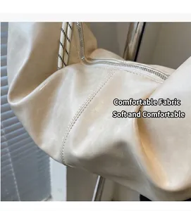 Dettaglio della borsa beige in ecopelle con pieghe morbide e coulisse intrecciate bianche e nere
