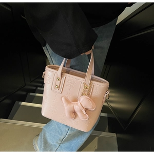 Dettaglio borsa a secchiello rosa con goffratura a stelle, ciondolo peluche e hardware oro