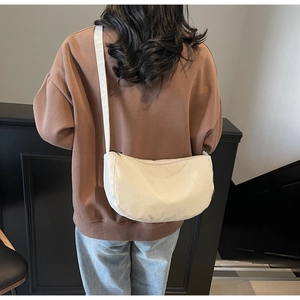 Close-up of minimalist off-white crescent crossbody bag with smooth nylon texture