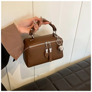 Detailed macro view of dark brown pebbled leather texture and silver zipper of boston bag