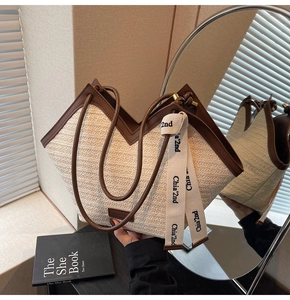 Dettaglio della borsa tote in paglia avorio con finiture in pelle marrone e nastro decorativo