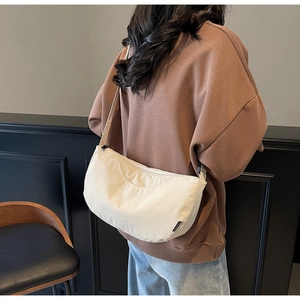 Lifestyle shot of an off-white canvas crescent bag worn by a model in casual attire