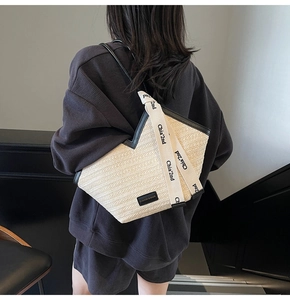 Dettaglio della borsa tote in paglia con finiture in pelle nera e manico in nastro