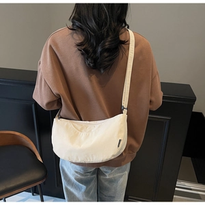 Close-up of minimalist white canvas crescent bag with adjustable wide shoulder strap