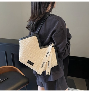 Vista dettagliata della borsa tote in paglia intrecciata con manici in pelle nera e loghi